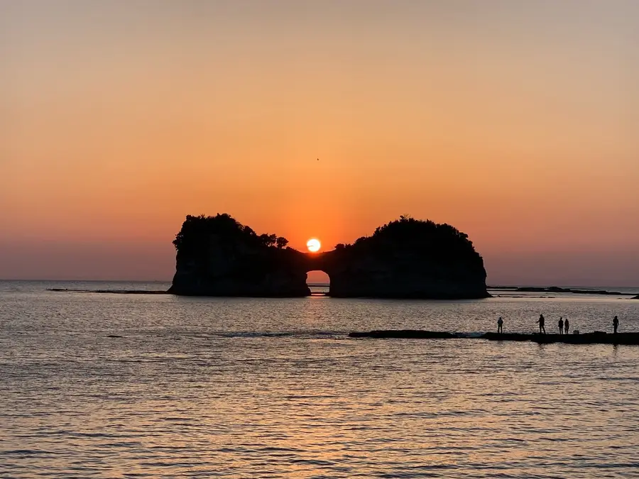 The sun setting through the sea arch of Engetsuto island off Shirahama, Wakayama